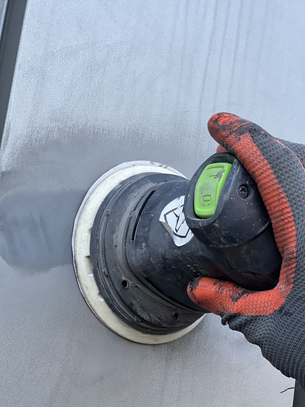 Expert van voortman coating aan het schuren als voorbereiding op het overspuiten van gevelblekleding