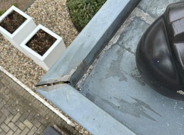 Gescheurde hoeknaad in oude zinken dakgoot vóór herstel