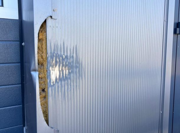 Detailfoto van vervormd gevelpaneel met deuk en scheur