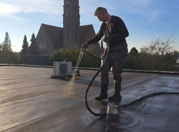 Medewerker spuit vloeibare dakcoating voor waterdichte afwerking