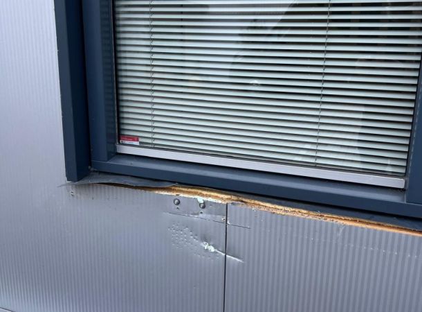 Detail van beschadigd gevelpaneel bij bedrijfsgebouw