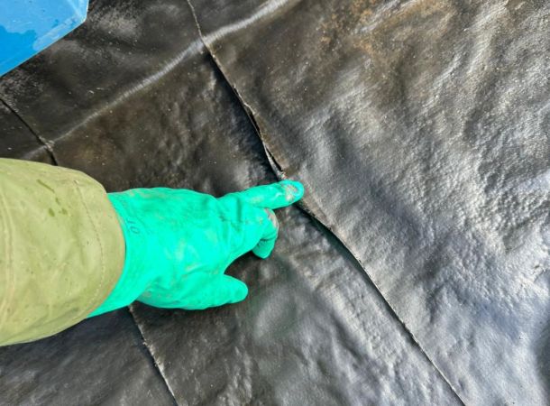 Vinger wijst scheur aan in oude dakgoot voor herstel